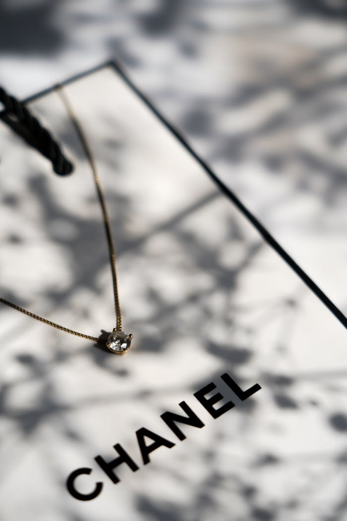 Delicate necklace on a Chanel gift box with soft shadows creating a luxurious feel.