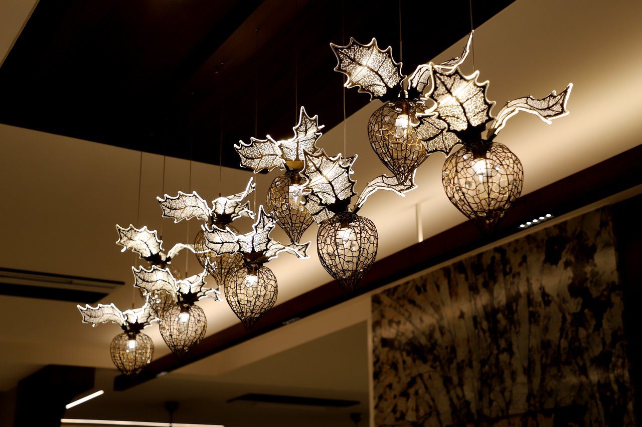 A striking indoor chandelier with intricate holly leaf glass designs, perfect for adding elegance.